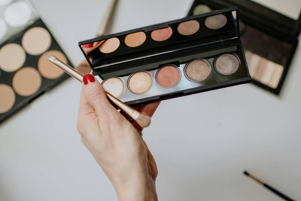 Hand holding an eyeshadow palette and brush